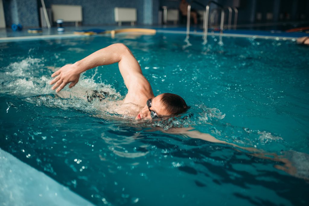 Homme qui s'entraîne dans une piscine en suivant un programme de musculation pour la natation