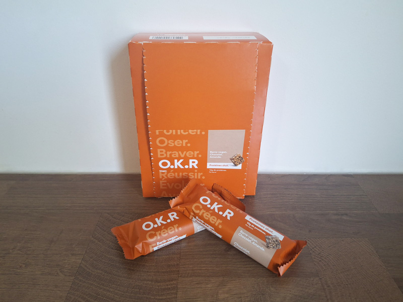 Photo des barres aux céréales O.K.R parfum amande chocolat à côté de leur boîte