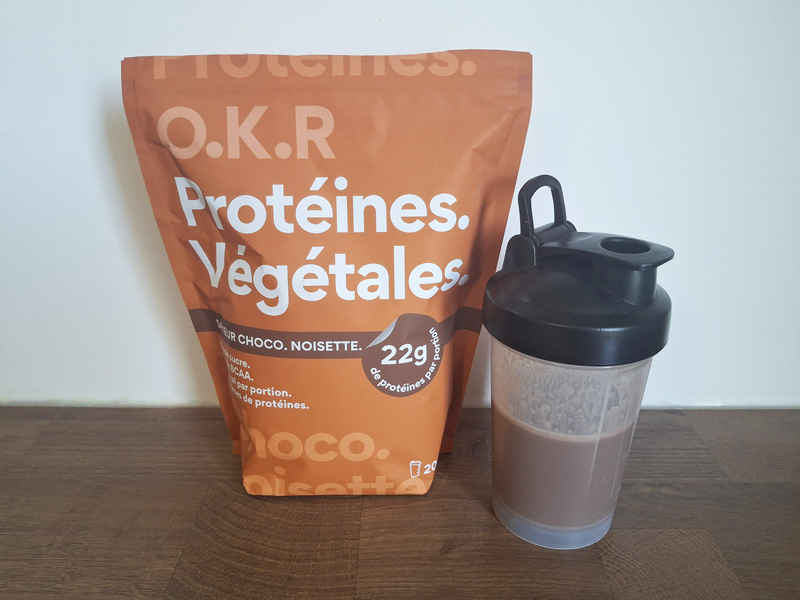 Photo du sachet de protéine en poudre O.K.R goût chocolat et d'un shaker rempli