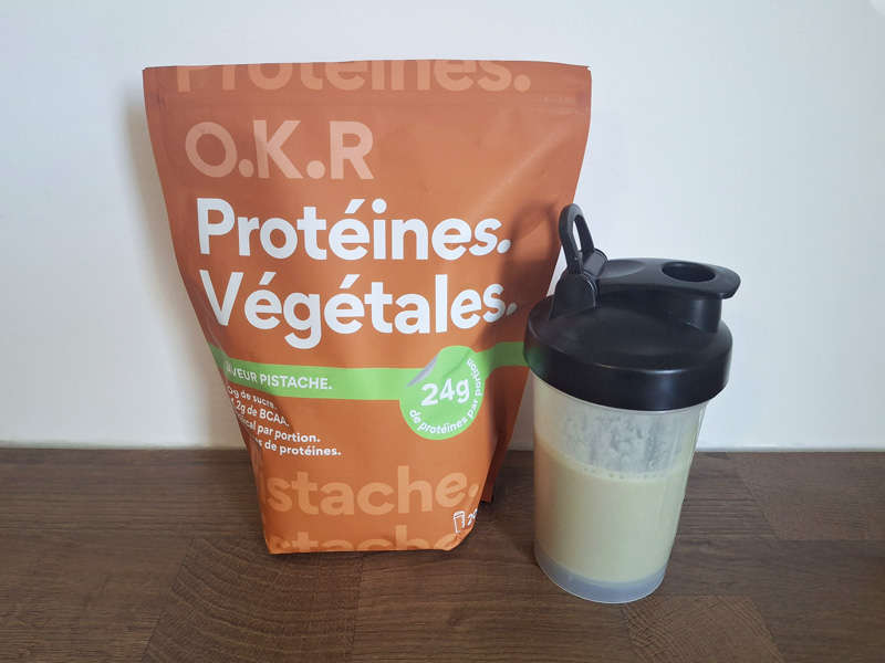 Photo du sachet de protéine en poudre O.K.R goût pistache et d'un shaker rempli